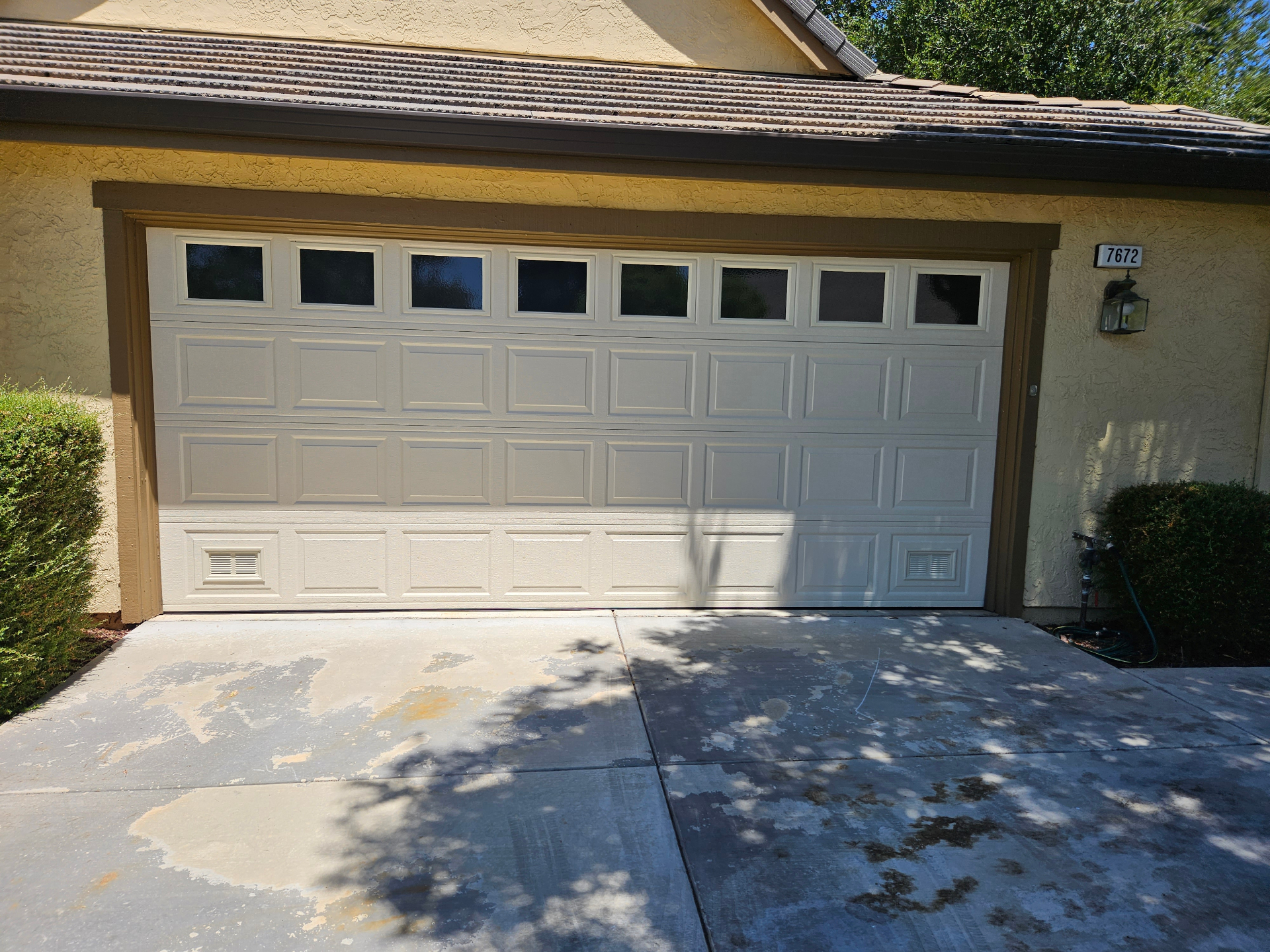 Residential raised-panel garage door with windows serviced by Al's Automatic Gate