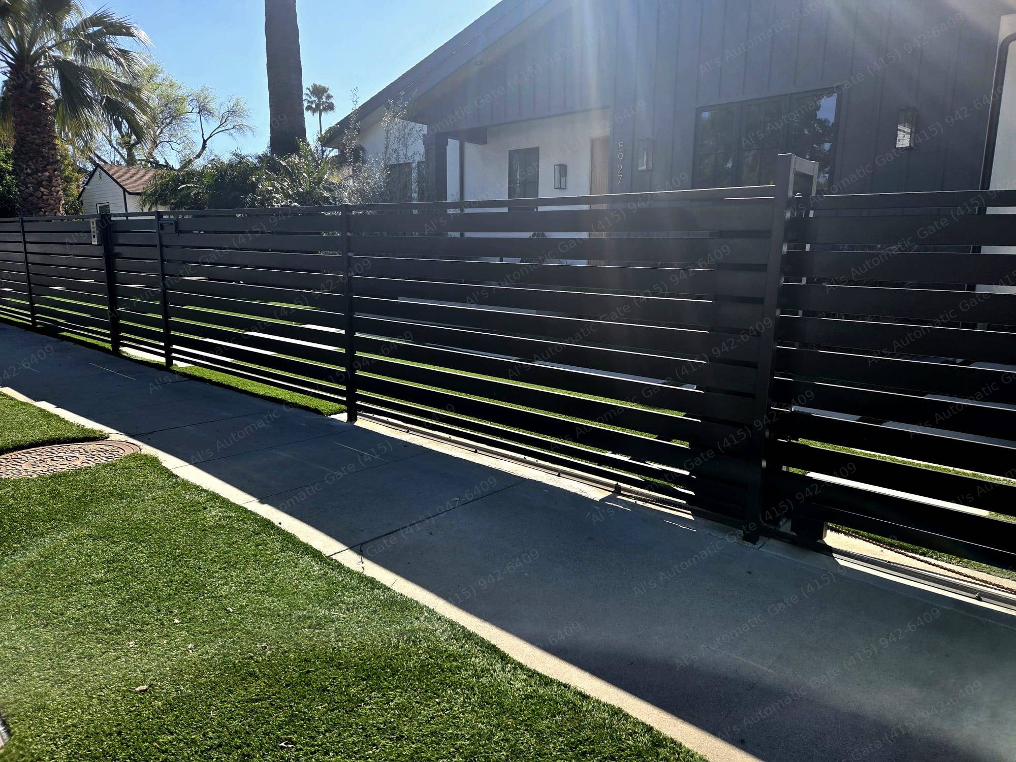 Black horizontal-slat automatic sliding driveway gate installed by Al's Automatic Gate