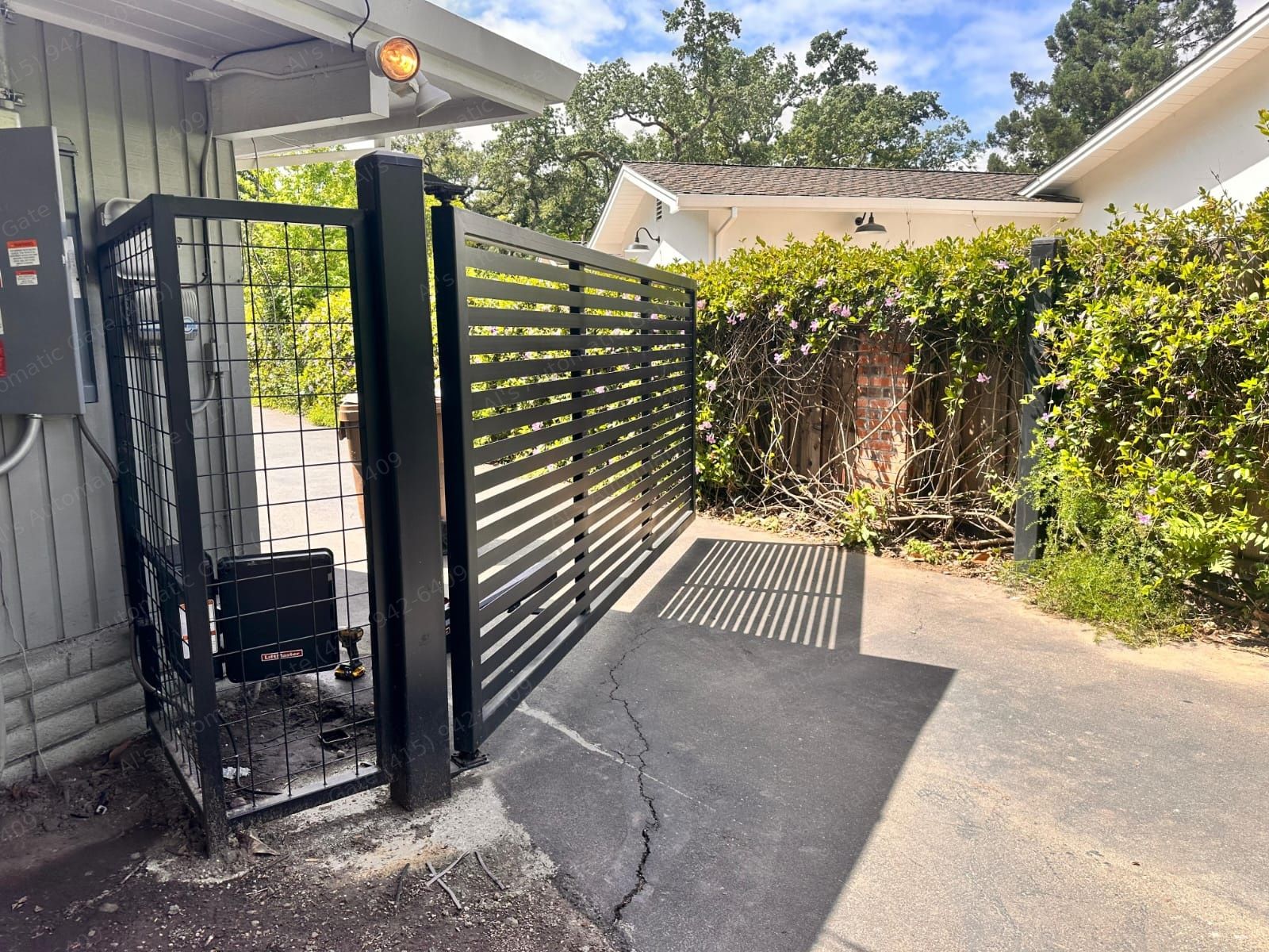 Black slat swing gate with LiftMaster operator in a mesh enclosure
